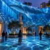 Immersive Ocean Experience transforming an open-air courtyard with projected whales, jellyfish, schools of fish, and underwater light surrounding visitors.