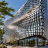 Wind moves thousands of small metal panels across Kinetic Building Façades, creating visible ripples of motion across a modern architectural exterior.