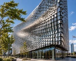 Wind moves thousands of small metal panels across Kinetic Building Façades, creating visible ripples of motion across a modern architectural exterior.